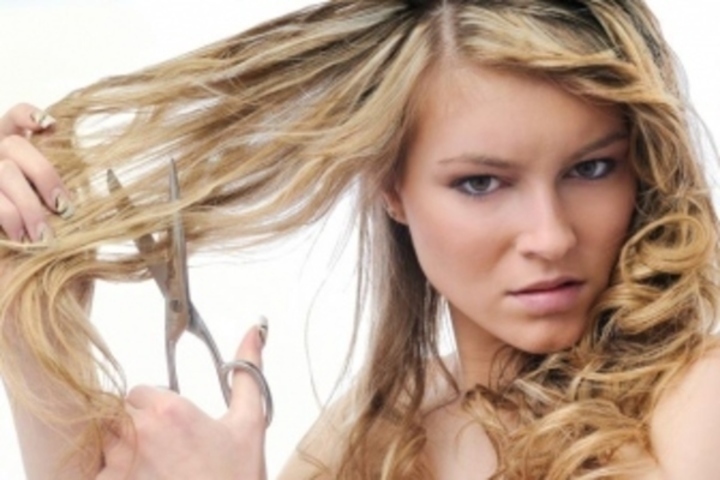 Žena držící nůžky u svých vlasů 