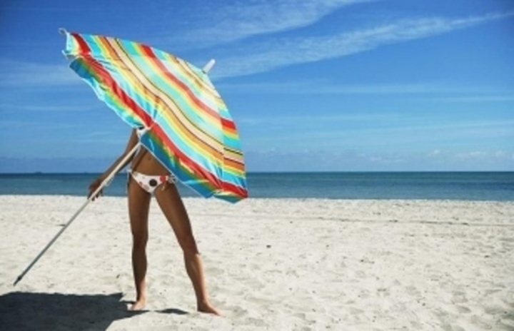 Žena držící slunečník na pláži 