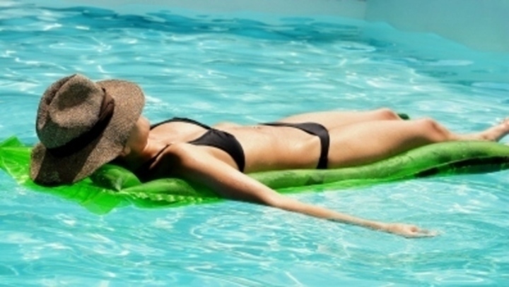 Žena v bazénu ležící na lehátku