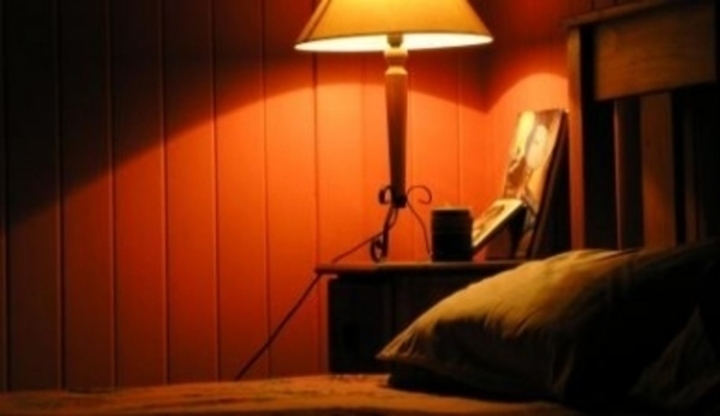 Lampa svítící na nočním stolku u postele 