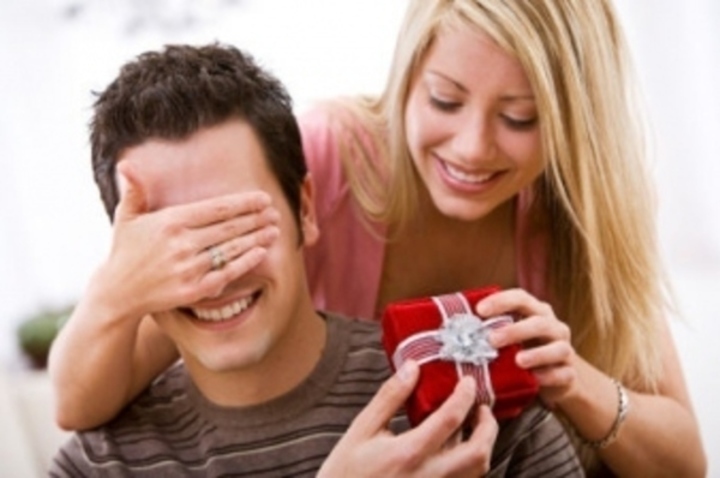 Žena zakrývající oči muži při předávání dárku 