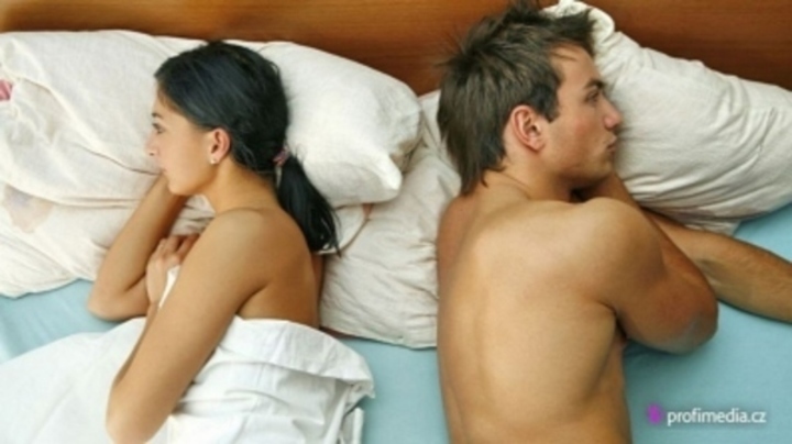 Dvojice ležící v posteli zády k sobě  