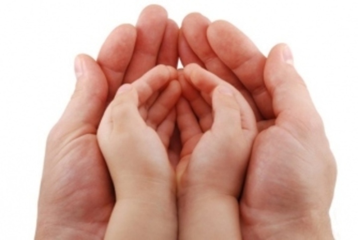Ruce dítěte položené v dlaních dospělého člověka