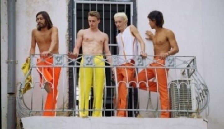 Čtyři muži stojící vedle sebe na balkóně 