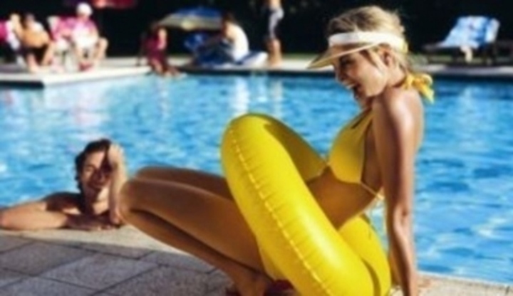 Žena se žlutým nafukovacím kruhem u bazénu 