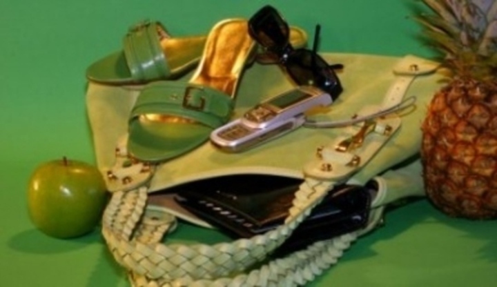Zelená kabelka se zelenými boty,jablkem,ananasem a položeným telefonem s brýlemi 
