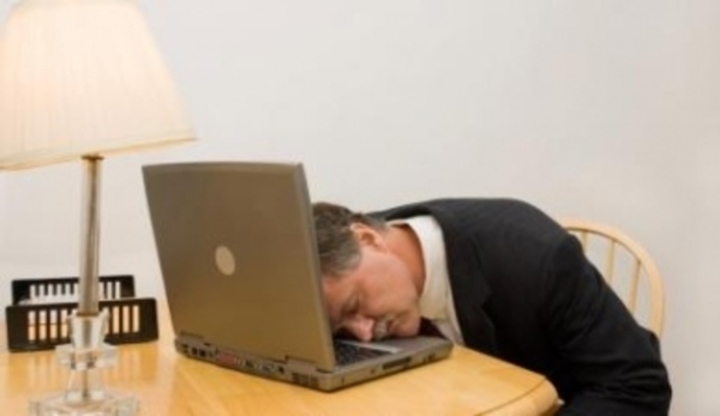 Muž ležící hlavou na klávesnici notebooku 