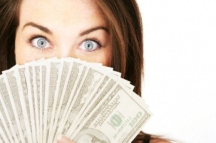 Žena se stodolarovými bankovkami před obličejem 