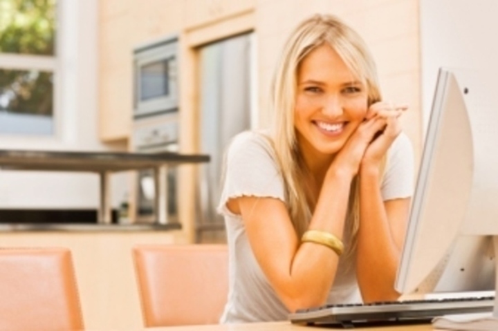 Žena s úsměvem sedící u počítače 