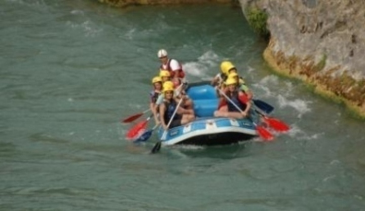 Lidé v přilbách plující po řece na člunu 