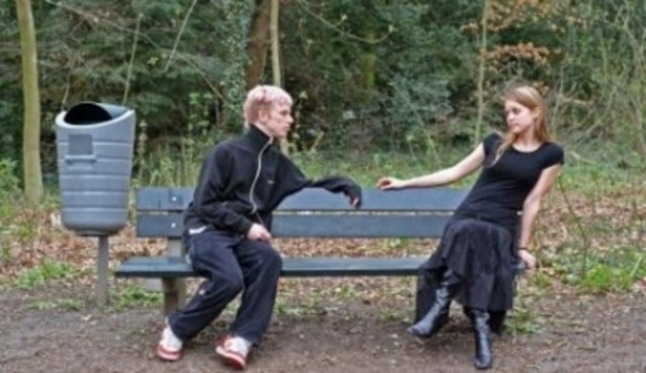 Muž se ženou sedící na lavičce daleko od sebe