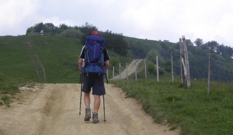 Muž s batohem na zádech jdoucí do kopce 