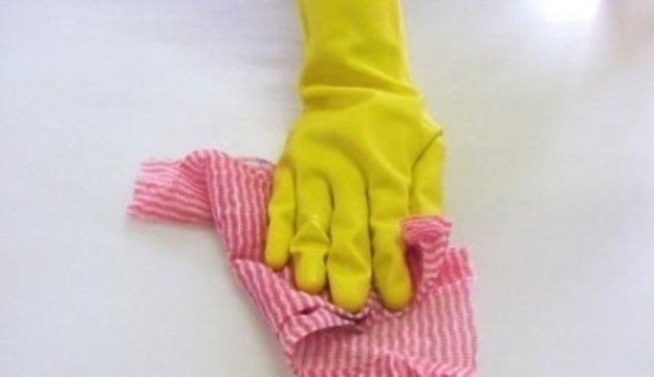 Ruka v žluté gumové rukavici držící hadřík 