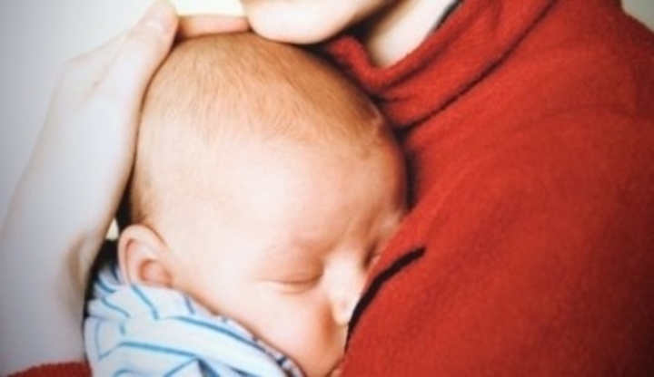 Matka držící své dítě přitisknuté na hrudi 