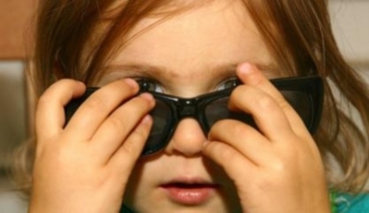 Malá holčička nasazující si sluneční brýle 