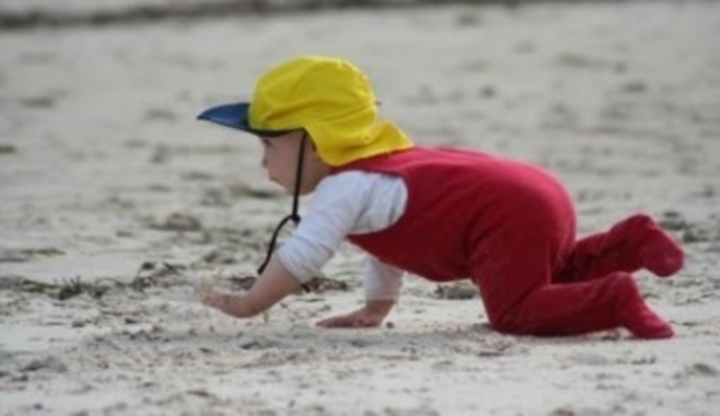Dítě chodící po čtyřek na písečné pláži 
