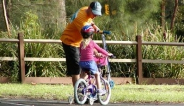 Otec učící dítě jezdit na kole 