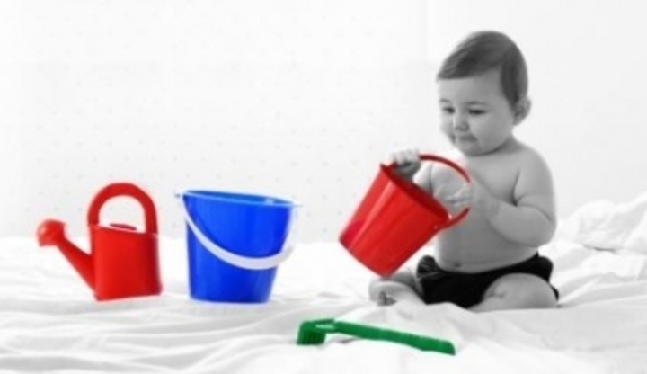 Dítě hrající si s kyblíčky a konvičkou 