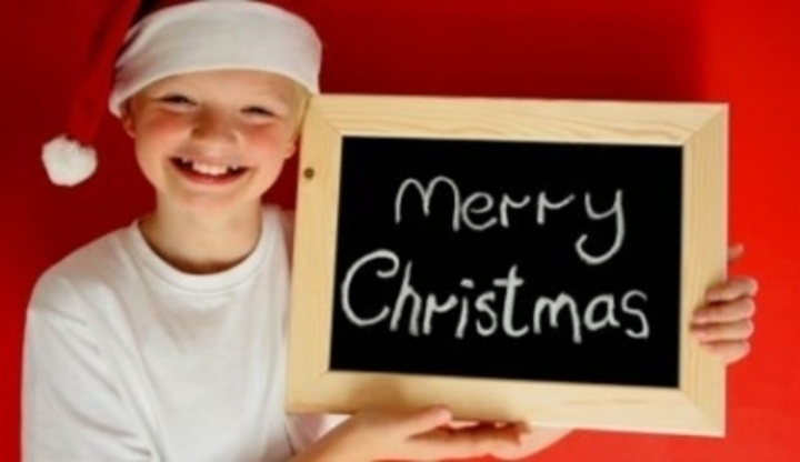 Chlapec v čepici držící ceduli s nápisem Merry Christmas 