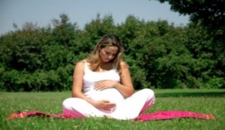 Těhotná žena sedící na louce 
