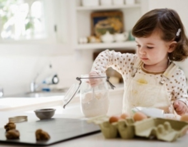 Dítě v kuchyni sahající do sklenice s moukou