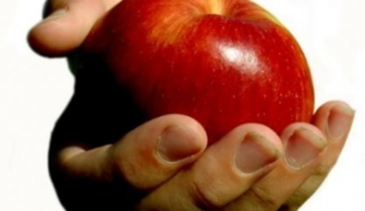 Ruka držící červené jablko 
