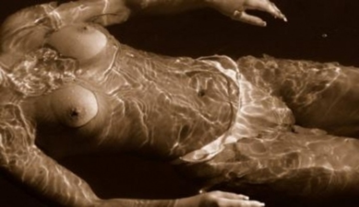 Žena ležící ve vodě s odhaleným poprsím 