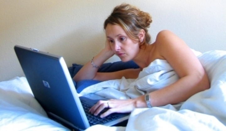 Žena s notebookem ležíc v posteli