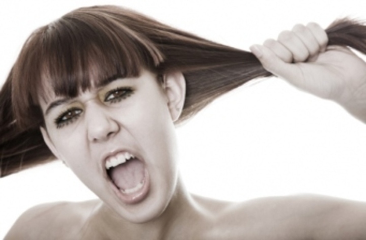 Žena s otevřenou pusou držící své vlasy