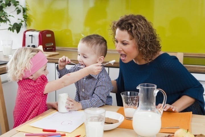Žena s dětmi u stolu se snídaní 