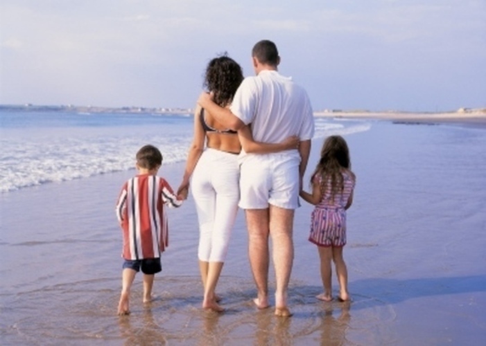 Rodiče s dětmi procházející se po pláži 
