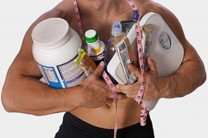 Muž držící v náruči osobní váhu a různé dietní přípravky