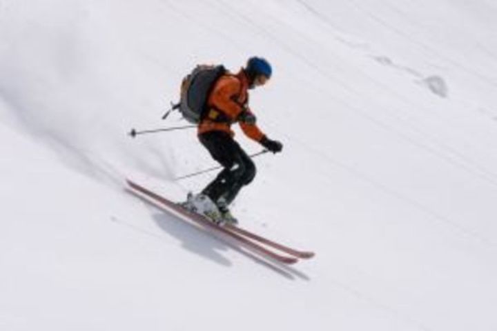 Muž na lyžích jedoucí z kopce dolů 
