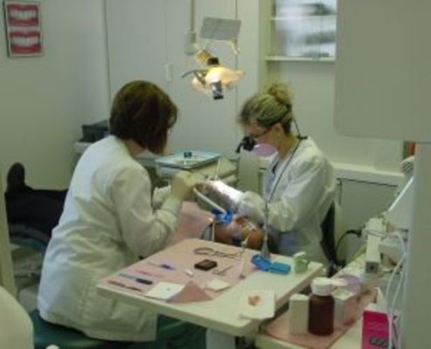 Ženy v ordinaci opravují zuby ležícímu muži 