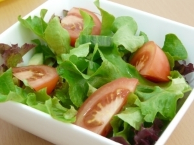 Salátové listy s nakrájenými rajčaty v misce 