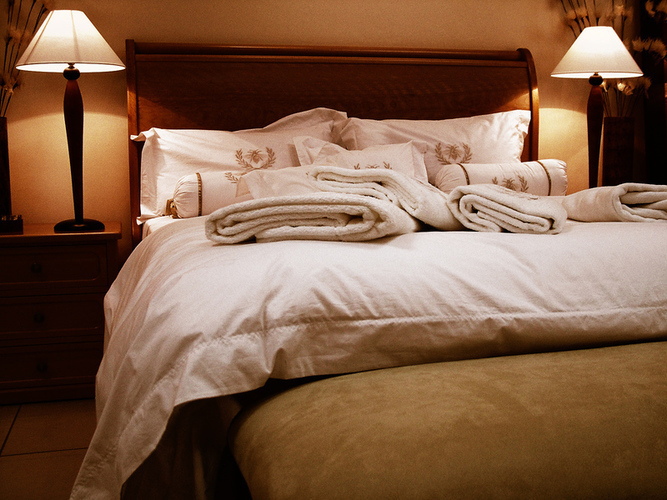 Ložnice s manželskou postelí a dvěma rozsvícenými lampami