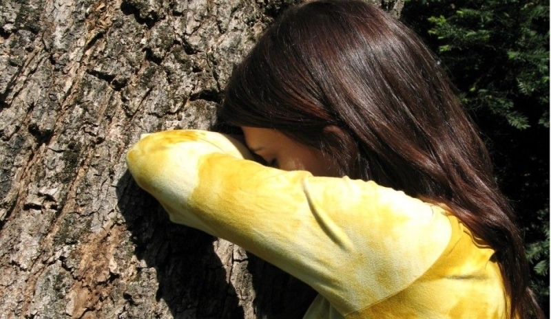 Dívka opřená rukou o strom 