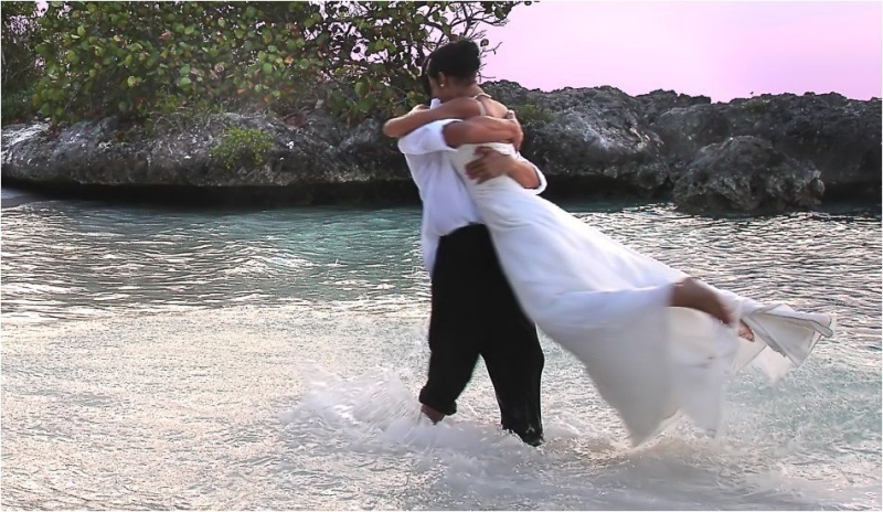 Muž stojící ve vodě objímá ženu v šatech 
