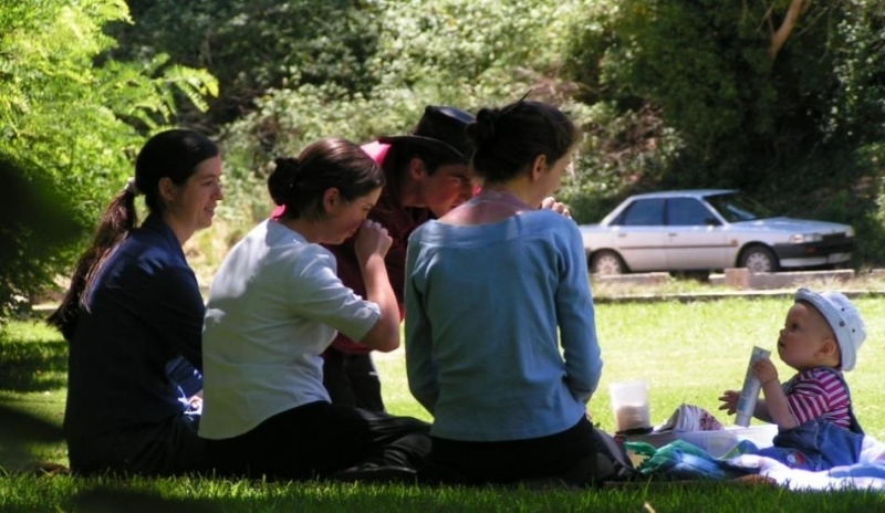 Lidé sedící s miminkem na trávě 