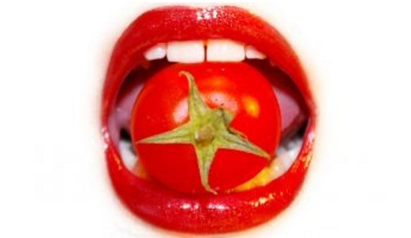 Červené ústa držící rajče 
