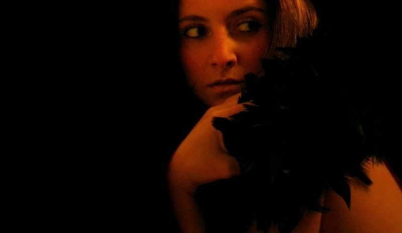 Žena ve tmě s černým peřím kolem ramen 