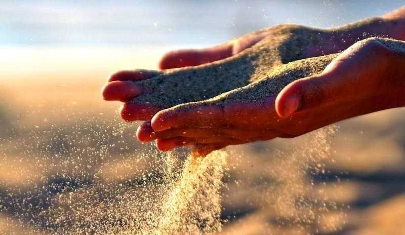 Písek padající mezi prsty 